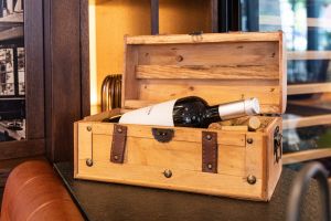 Eine geöffnete Holzschatulle mit einer Weinflasche der Marke „Anima Negra“. Neben der Flasche liegen mehrere Korken in der Schatulle.